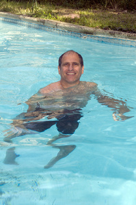 微笑着中年帅哥在游泳池中游泳