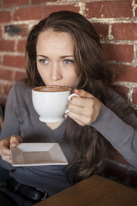 年轻女子与美丽的绿色眼睛与白咖啡杯子