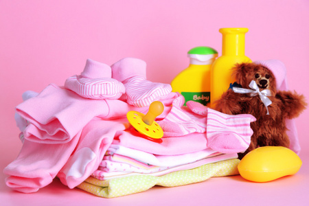 堆在粉红色的背景上的婴儿衣服