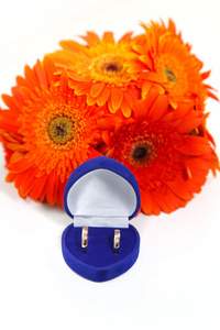 两个黄金结婚戒指与橙色扶郎花花束
