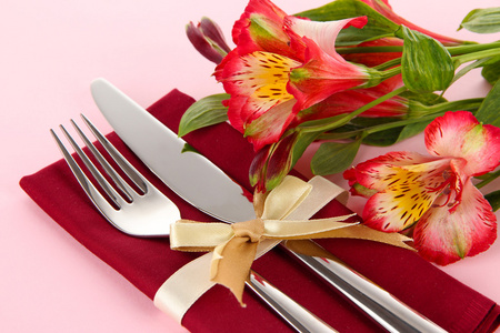 节日餐桌设置与粉红色的背景上的花朵