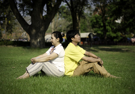 美丽的夫妇坐在公园里的地面上的肖像
