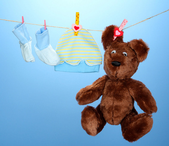 婴儿衣服挂在晾衣绳上，在蓝色背景上