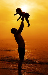 父亲和女儿一起在海滩上玩在日落时