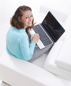 快乐年轻女子坐在沙发和一台笔记本电脑