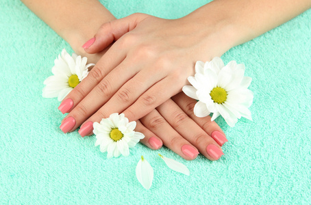 女人手中粉红色修指甲和鲜花的色彩背景