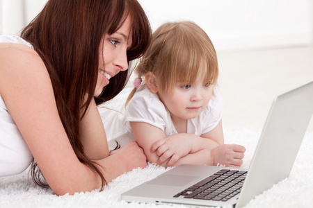 快乐年轻的母亲和她的女儿使用一台笔记本电脑
