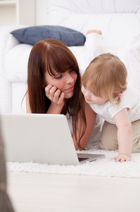 快乐年轻的母亲和她的女儿使用一台笔记本电脑