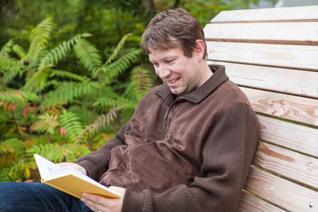 阅读本书在夏季森林在长凳上的年轻人