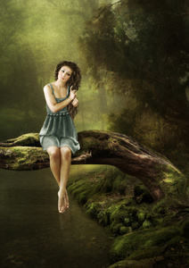 女孩坐在一棵树上在水