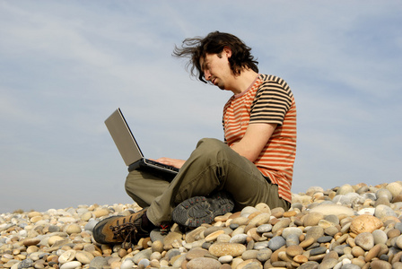 笔记本电脑在海滩上休闲的年轻人