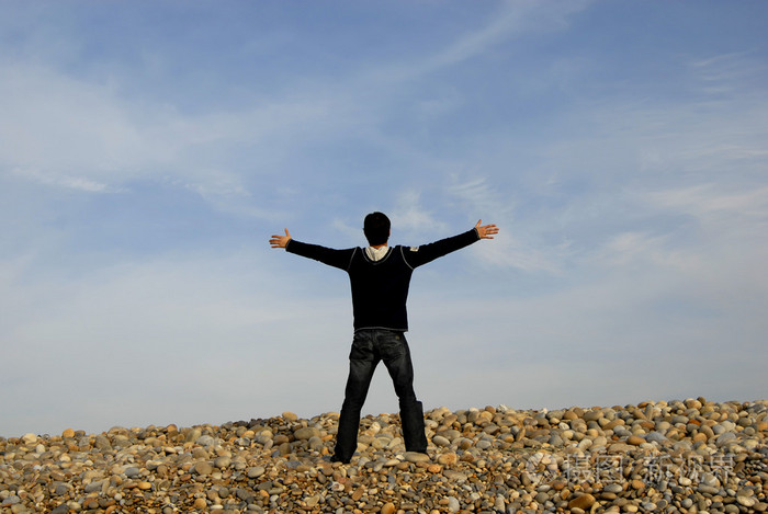 敞开双臂在海滩上的人