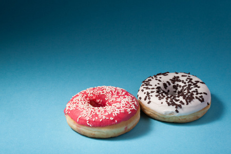 两个甜甜圈有孤立在蓝色背景上的红色和白色糖衣照片