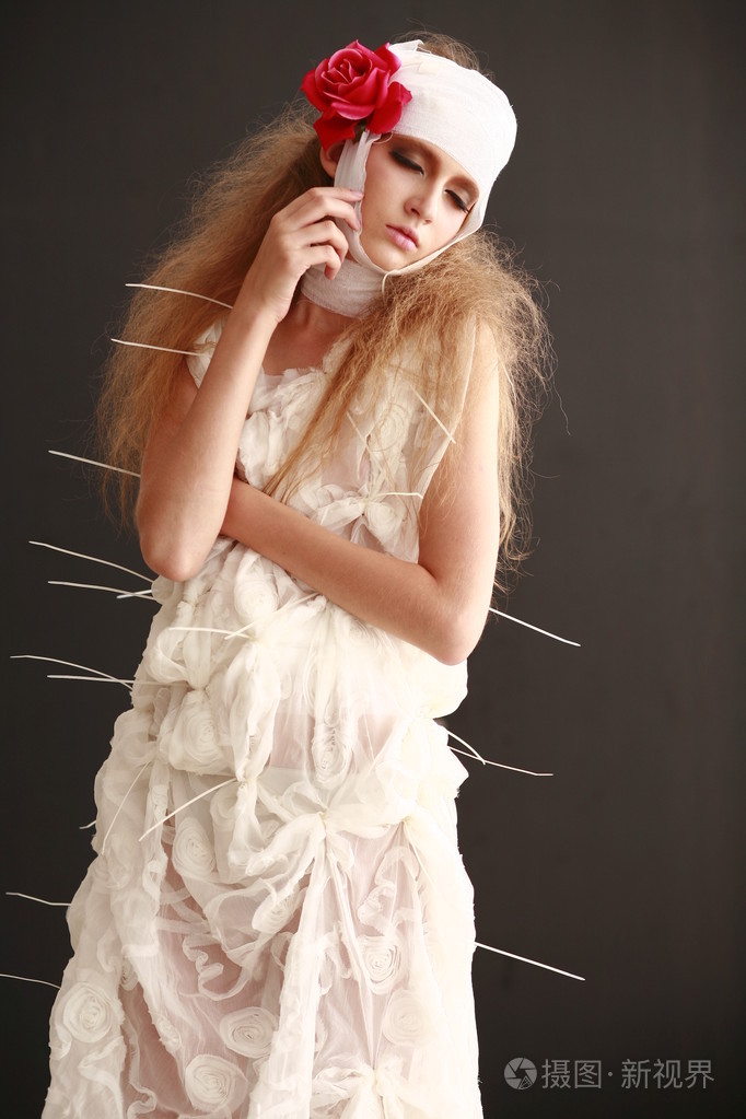 年轻的, 脆弱的女孩站在浴袍和绷带的头,生病的红色花