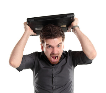 愤怒的商人盯着他的笔记本电脑,大喊照片