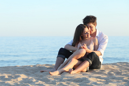 情侣拥抱坐在海边的沙滩上