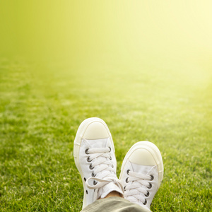 一双白色运动鞋在阳光下的草