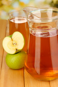 全玻璃和苹果汁和苹果在室外的木桌上的水壶