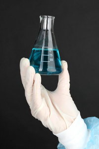 与流体在黑色背景上的医疗测试期间的科学家手中的玻璃管