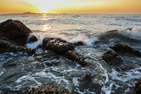 海浪在日落时撞到石头