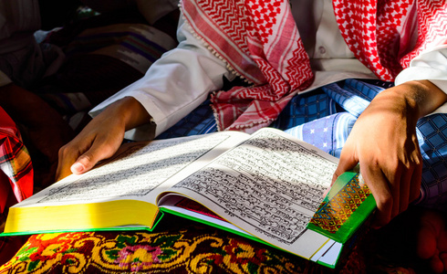 朝圣者男孩一个年轻的穆斯林男孩读古兰经 》照片