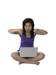 亚洲女人显示拇指向下同时使用的便携式计算机