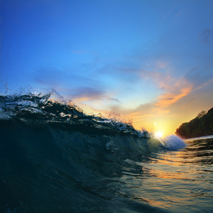 在日落时掉下来的粗糙彩色的海洋波