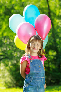 在绿色公园举行彩色气球的小小快乐女孩