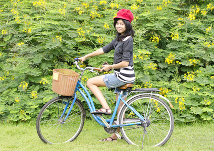 自行车在公园微笑的年轻漂亮女人