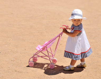 可爱的小女孩与玩具婴儿小推车