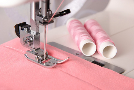 缝纫玫瑰色布料机和两个线轴上的进程