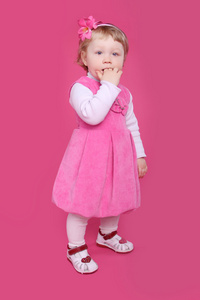 有趣的小女孩站在粉红色bac的全长肖像