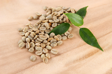 绿色咖啡豆和木制背景上的叶子