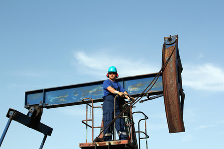 石油工人戴墨镜站在泵杰克图片
