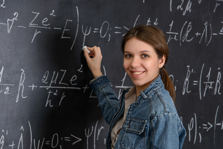 漂亮的学生在做数学黑板上的肖像