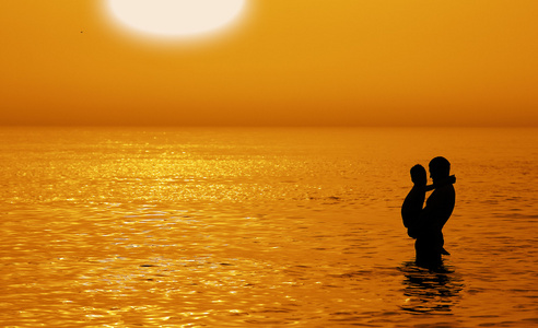 far och son simning i havet vid solnedgngen