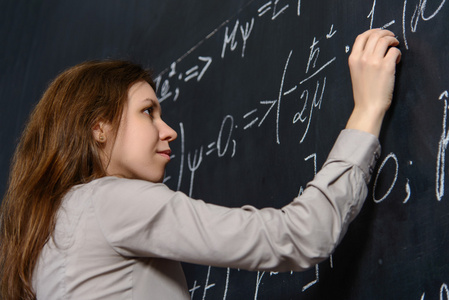 漂亮的学生在做数学黑板上的肖像