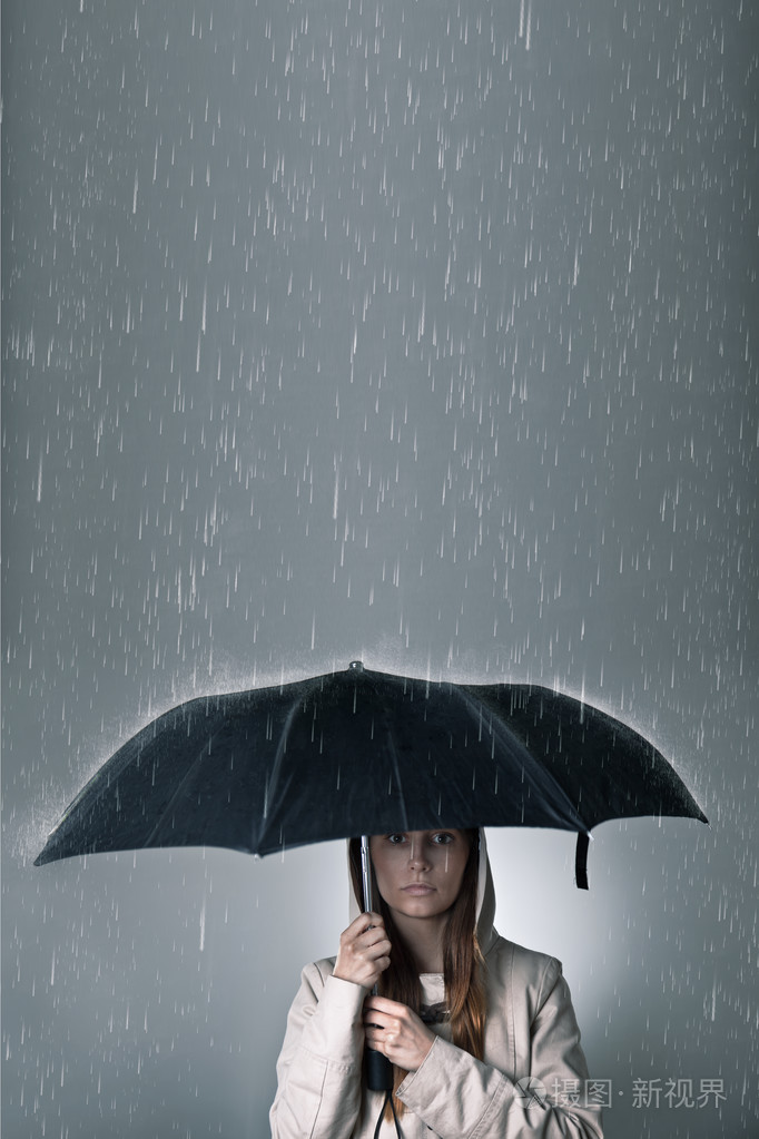 年轻女子在降雨期间伞下