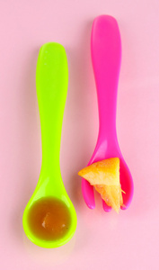 颜色的叉子和勺子的粉红色背景上的婴儿食品