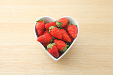 草莓的心形状碗木制背景上