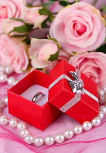 玫瑰和粉红布上的订婚戒指图片