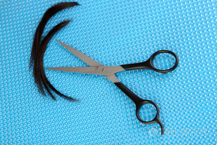 蓝色背景上用剪刀剪头发的片断