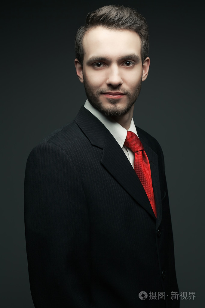 年轻英俊的男人 (商人) 在黑色西装的机智的肖像照片-正版商用图片1c