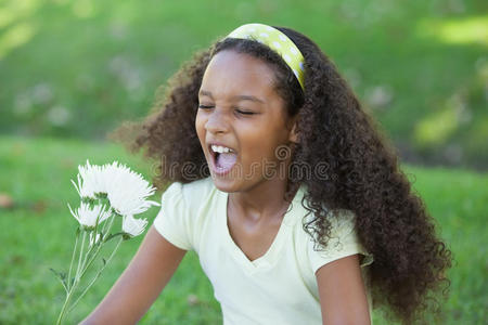 在公园里捧着花打喷嚏的小女孩