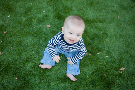 快乐的宝宝坐在绿色的草坪上
