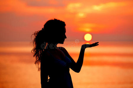 快乐自由的女人在海上享受夕阳。轮廓与
