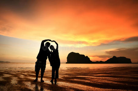 牵手夕阳浪漫的情侣在海滩上的夕阳下牵手照片