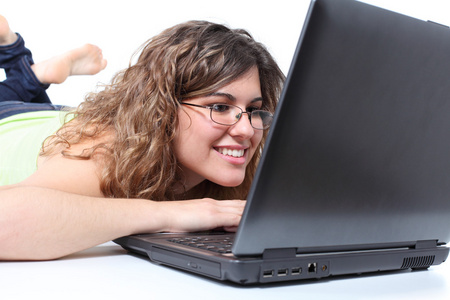 美丽的女人躺在和一台笔记本电脑在浏览