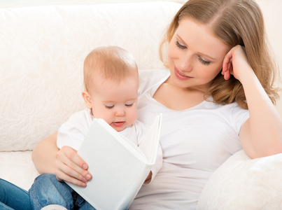 读一本书在沙发上的小宝宝的母亲