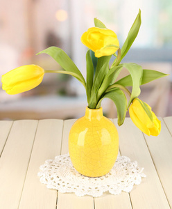 房间背景上的木桌上花瓶里的黄色郁金香